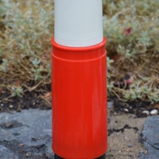 A red vacuum flask standing on gravel