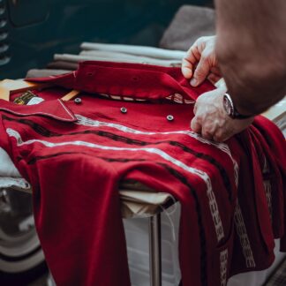 A deep red knit longsleeve being folded