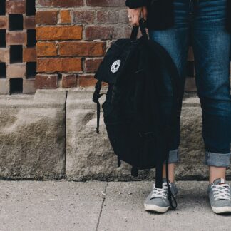 A slim black city pack carried on one shoulder
