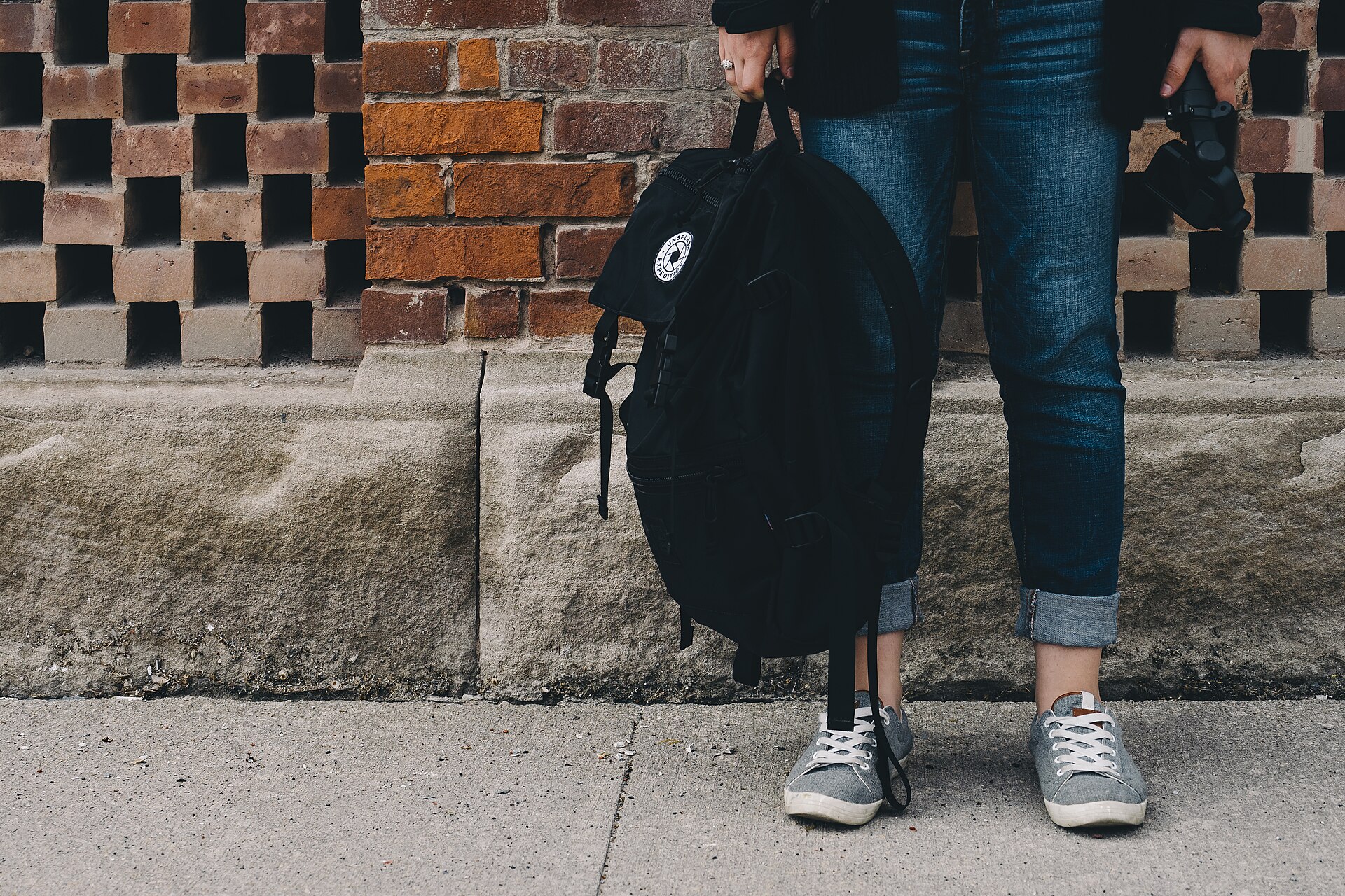 A slim black city pack carried on one shoulder